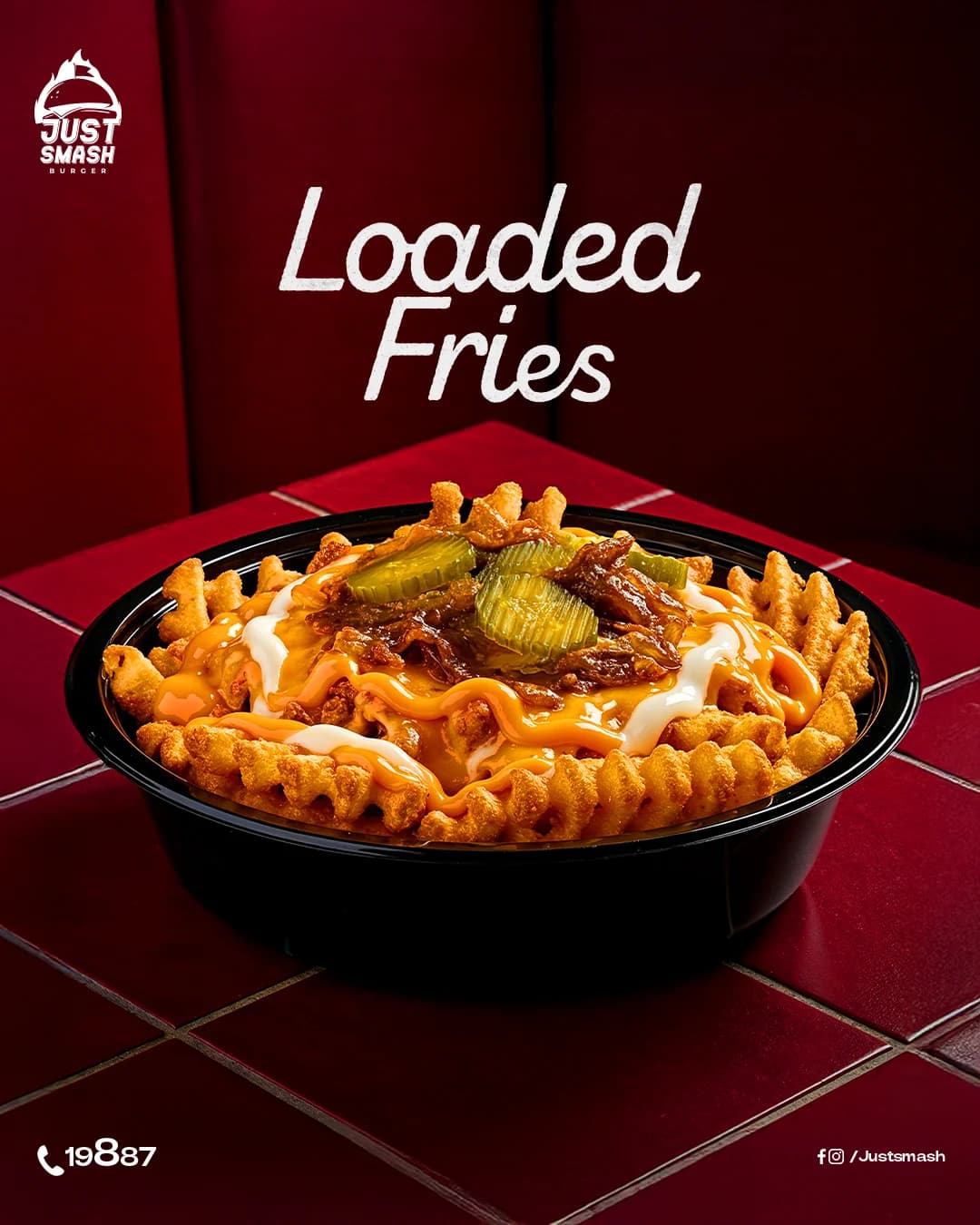 Just Smash Burger loaded fries post: a bowl of waffle fries topped with cheese sauce, mayo, pickles and caramelised onions on a red tiled table